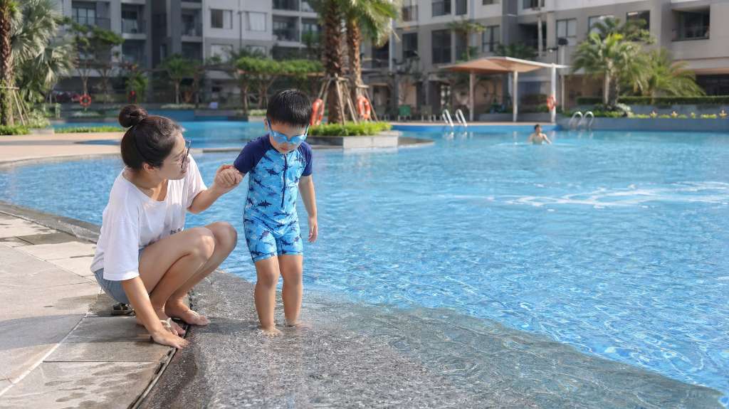Mẹ dắt bé tập làm quen với bể bơi ngoài trời